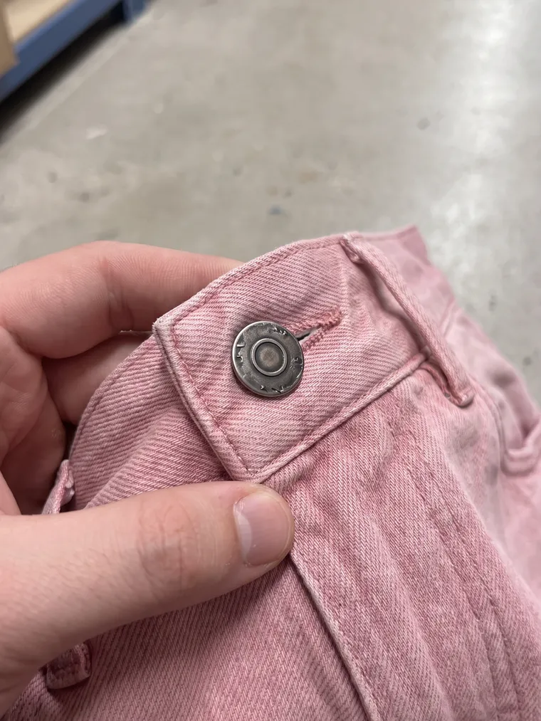 Phone photo: a hand holding up the waistband with the button
