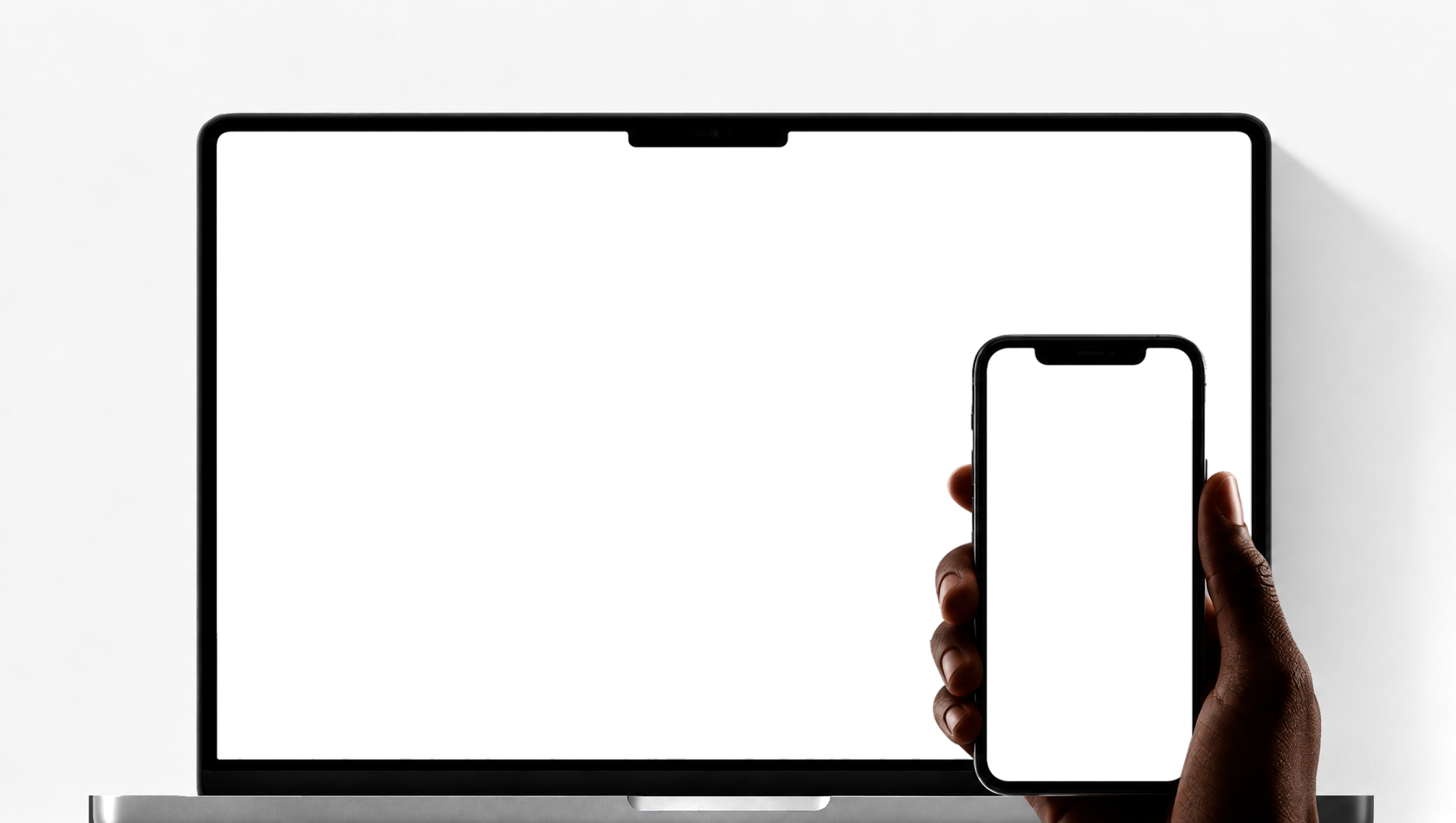 A laptop on a desk with a hand holding a phone in front of it
